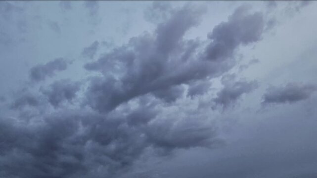 4K timelapse of dramatic storm clouds moving across an overcast sky, creating a moody atmospheric background with dynamic weather, natural texture and copy space.