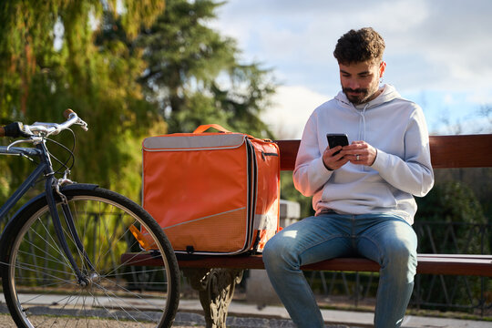 Courier checking smartphone while resting during delivery job