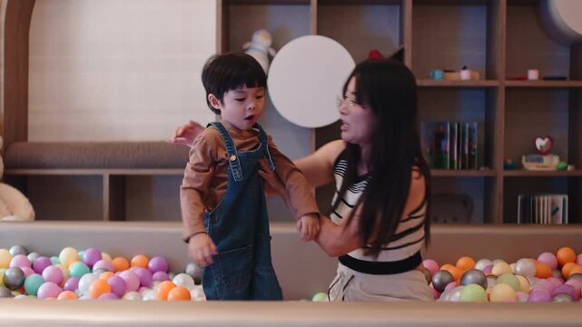 Mother and son high fiving while playing in a colorful ball pit
