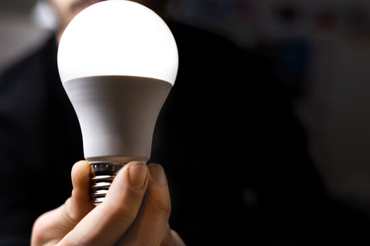 Hand holding a bright, glowing led light bulb, symbolizing new ideas and innovation