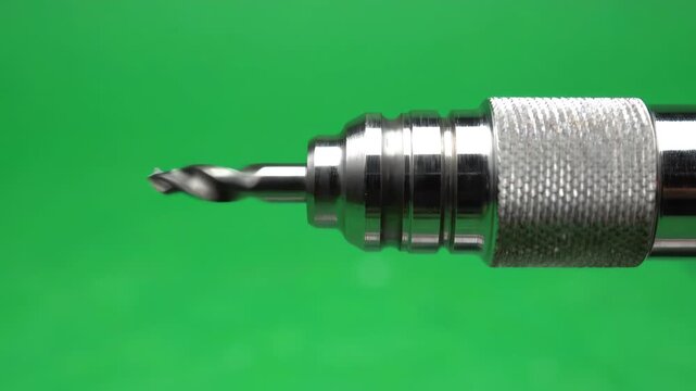 A precision stainless steel pin vise hand drill rotating steadily against a solid green screen background for chroma key compositing