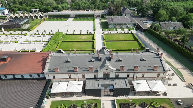 Aerial view of a formal garden with rectangular lawns and neatly trimmed boxwood hedges. Overhead perspective shows the estate's symmetrical layout and surrounding structures