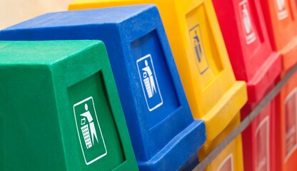 Row of colorful recycling bins for waste management and environmental sorting in an outdoor public space © Arslan Saeed