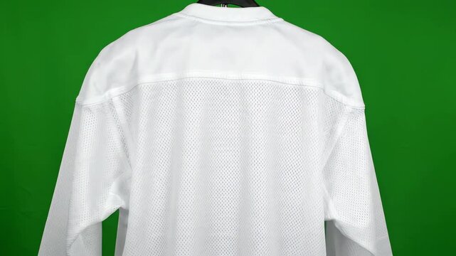 Blank white hockey jersey with mesh texture hanging and rotating slowly against a bright chroma key green screen background