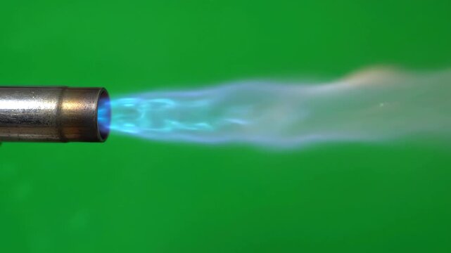 Blue propane torch flame blasting from a metal nozzle against a chroma key green screen background for visual effects compositing