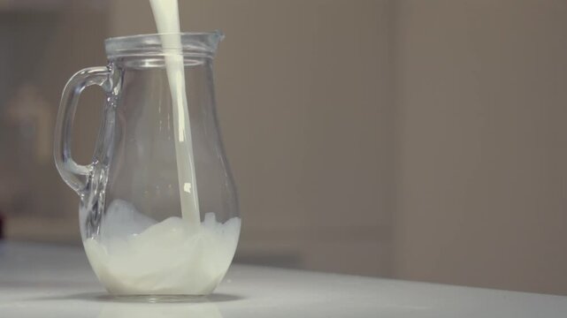 A quantity of milk is poured into a transparent jug in slow motion