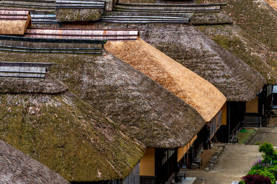 A traditional Japanese landscape featuring a row of thatched-roof houses.
