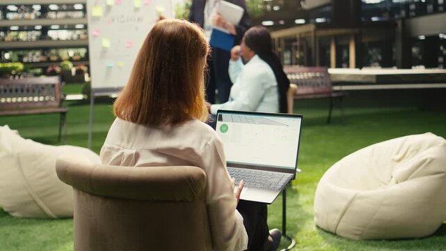 Businesswoman of photovoltaics data on laptop software for solar energy, screen shows green energy analytics dashboard with charts and renewable power metrics.
