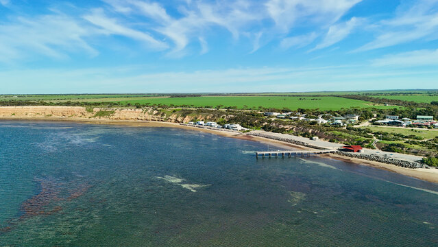Port Julia, Yorke Peninsula, South Australia &ndash; 4K aerial drone view of jetty, sheltered beach, limestone cliffs, coastal township and Gulf St Vincent, beachfront holiday homes, surrounding farmland