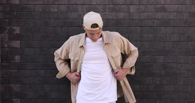 Young man wearing white t-shirt and stylish clothes near brick wall outdoors