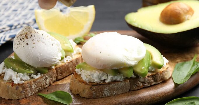 Woman adding spices to delicious avocado toasts at table, closeup