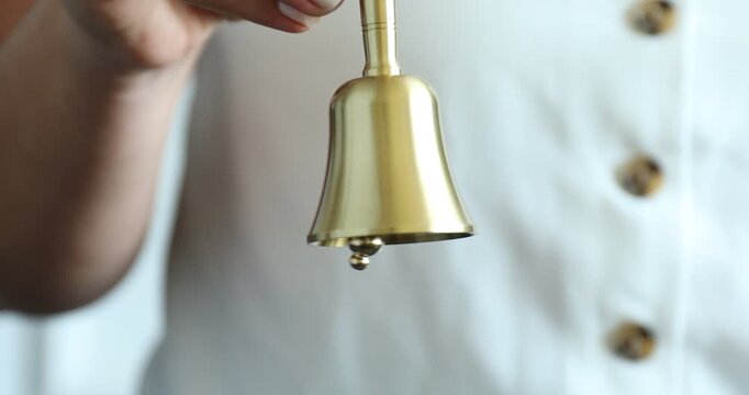 Woman ringing beautiful golden handbell indoors, closeup