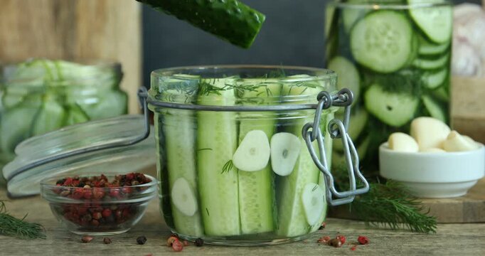 Taking pickled cucumber from jar at wooden table, closeup