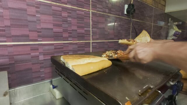A detailed view of a chef preparing a mouth-watering Turkish street food staple: a grilled kokoretsi sandwich, with sliced bread and finely chopped offal cooking on a flat griddle, ready to be served.