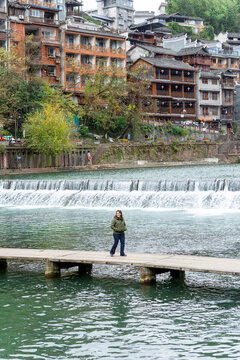 Woman walking on wooden stepping stone bridge in Fenghuang ancient town