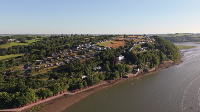 Aerial drone footage of the historic village of Laugharne in Carmarthenshire, Wales, featuring the River Coran estuary, traditional buildings, surrounding countryside and picturesque rural landscape 