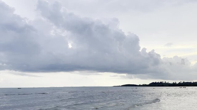 Calm ocean waves gently crashing on a sandy beach under a cloudy sky