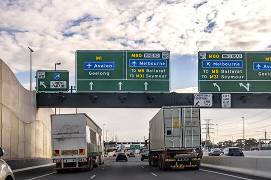 An overhead road signs direct traffic toward the M1 to Avalon and Geelong, the M80 Ring Road, Melbourne, M8 Ballarat, and M31 Seymour, over a busy multi-lane highway in Australia