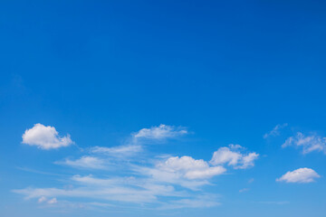 Fototapeta premium Vibrant blue sky background with scattered small white clouds