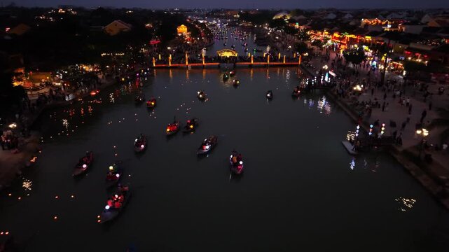 Boats navigate the illuminated river in Hoi An, Vietnam, as colorful lanterns reflect on the water, creating a lively and festive atmosphere