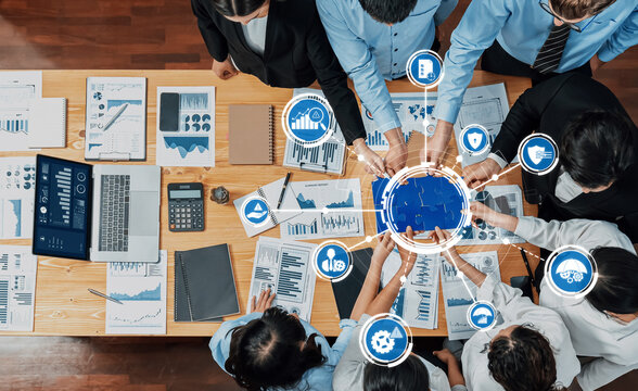 A dynamic business meeting with professionals collaborating over charts and data in a modern office, enhancing strategic management and decision-making processes. Amity