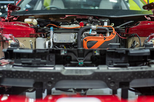 Internal view of modern EV powertrain and cooling system under the hood of a red car, real photo not AI.