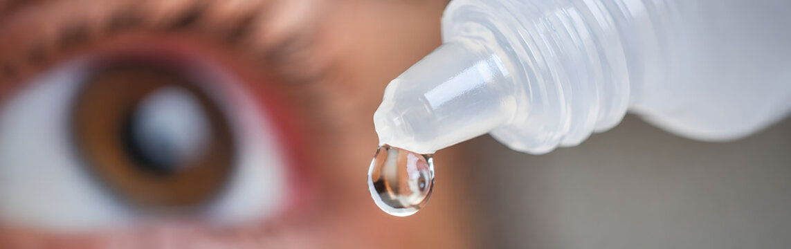 Eye drop falling into brown eye close up macro