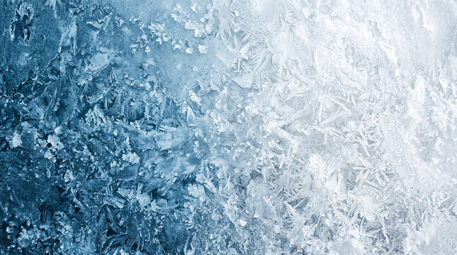 Frost crystals form intricate geometric patterns across a cold glass window pane during winter.