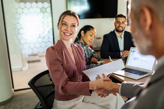 Smiling businesswoman shaking hands in modern office meeting