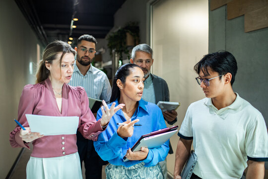 Coworkers discussing project while walking in office hallway