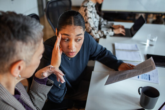 Concerned coworkers discussing a report in a modern office
