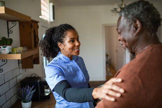 Home healthcare nurse supporting senior man in kitchen