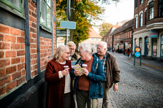 Senior friends sightseeing with map in historic old town