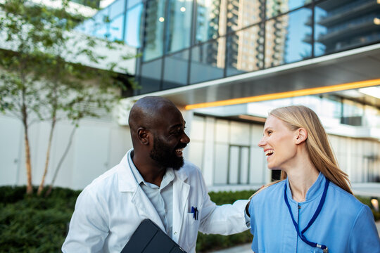 Doctor and nurse smiling together outside modern hospital