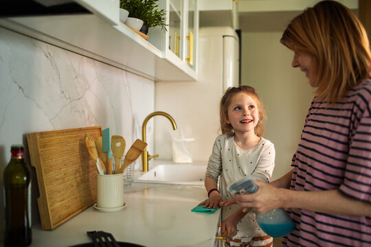 Mother and daughter cleaning kitchen counter at home