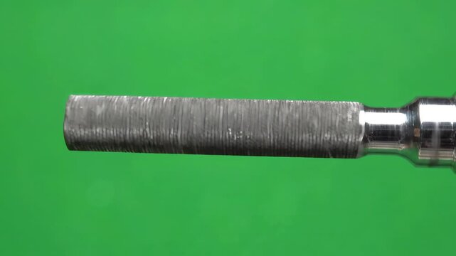 Metal round file tool rotating slowly on a bright green screen background for chroma key editing