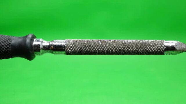 Metal rat tail file tool rotating slowly on a bright green screen background for easy chroma keying and post production