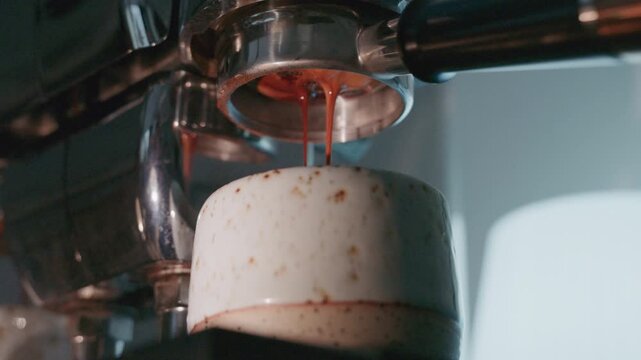 4K Pouring coffee stream from professional machine in cup. Barista man making double espresso, using filter holder. Flowing fresh ground coffee. Drinking roasted black coffee in the morning.	
