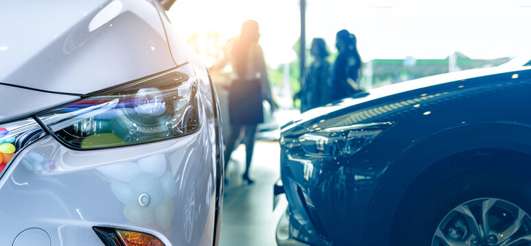 Selective focus a new car on blur saleswoman and customer in modern luxury showroom. Car dealership office concept. Dealer agent business. Automobile leasing service. Dealer company. New car purchase.
