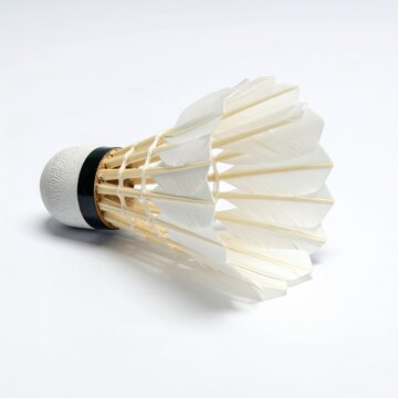 A white feathered shuttlecock rests on a clean white surface