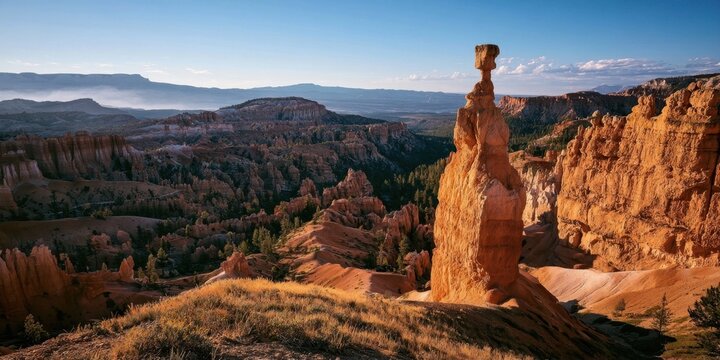 Red rock hoodoo formation towering over a sunlit canyon landscape at dawn