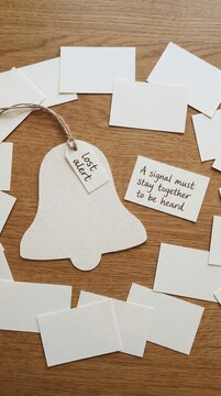 Paper Bell with 'Lost Alert' Tag and Message Surrounded by Scattered Notes on Wood for Low Attention Span