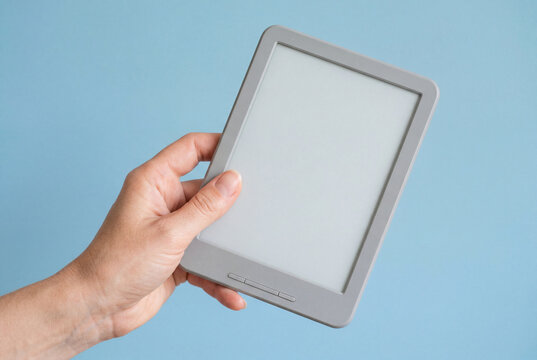 Hand holding grey electronic reader with blank screen on blue background