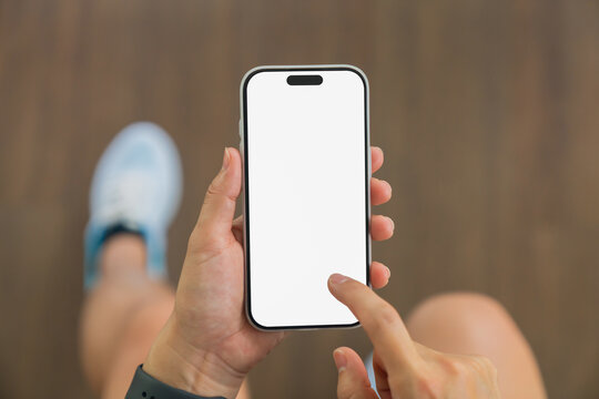 Person using smartphone with blank screen at gym.
