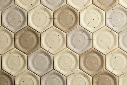 Geometric wall covering with repeating hexagonal ceramic tiles in shades of beige and grey featuring subtle radial lines and small dark spots