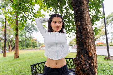 Obraz premium Asian sporty woman stretching before workout in public park