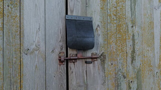 Handcrafted rain cover, rusty latch and aged timber shaped by years outdoors