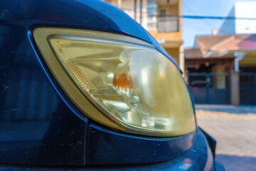 Close up view of a cloudy and yellowed old car headlight lens. Automotive part template for vehicle headlight restoration, cleaning service, or car detailing concept. © Anzz Stock
