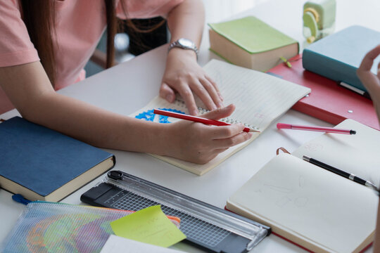 Two Asian girl with books on table doing homework together at home