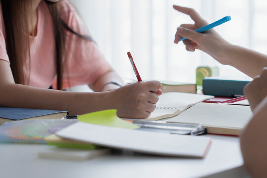 Two Asian girl with books on table doing homework together at home